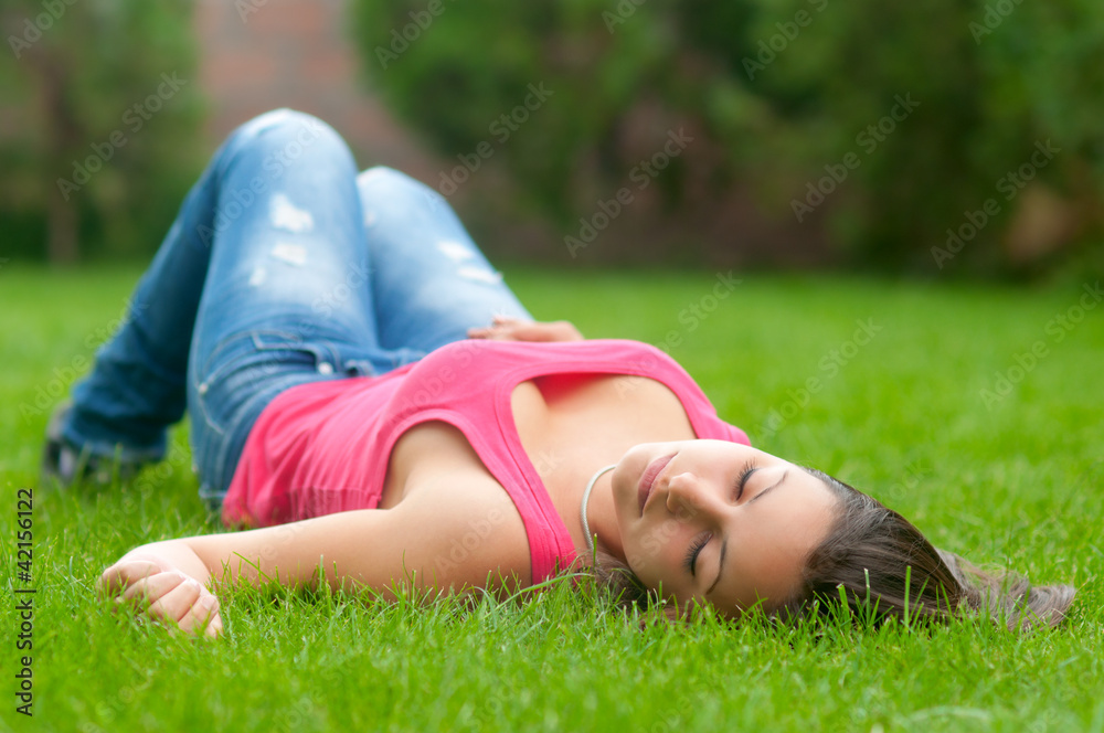 Beautiful girl lying on the grass on beautiful spring day Beautiful girl lying on the grass on beautiful spring day