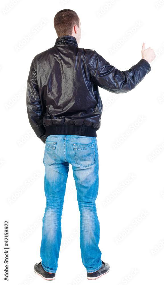 back view of standing young man showing thumb up back view of standing young man showing thumb up
