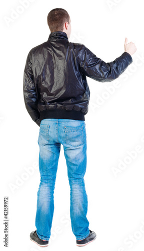 back view of standing young man showing thumb up