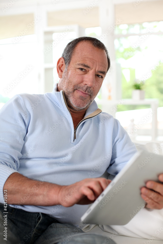 Senior man at home using electronic tablet