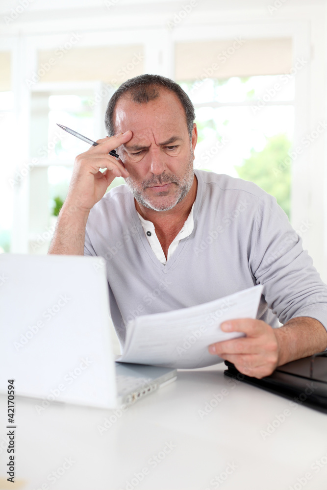 Senior man being puzzled with tax documents Senior man being puzzled with tax documents