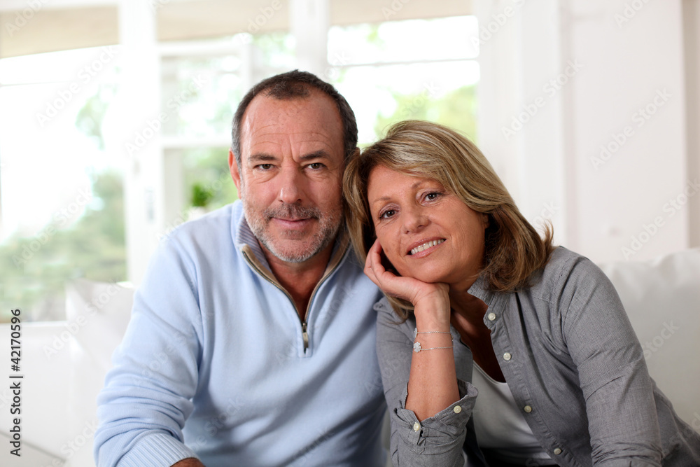 Portrait of happy senior couple sitting in sofa Portrait of happy senior couple sitting in sofa
