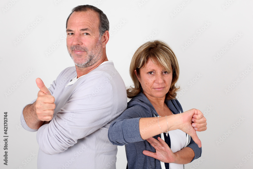 Senior couple with thumbs up and down Senior couple with thumbs up and down