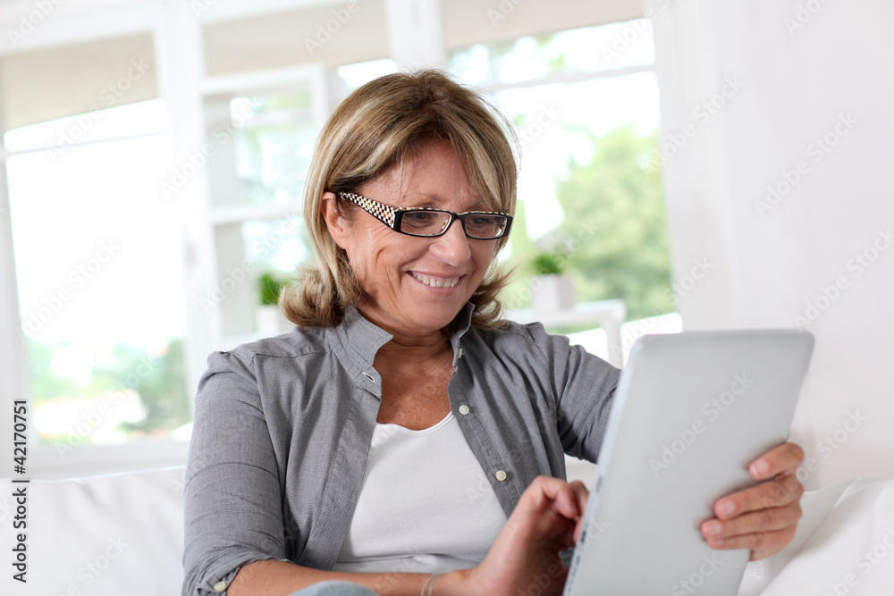 Smiling senior woman at home connected on internet