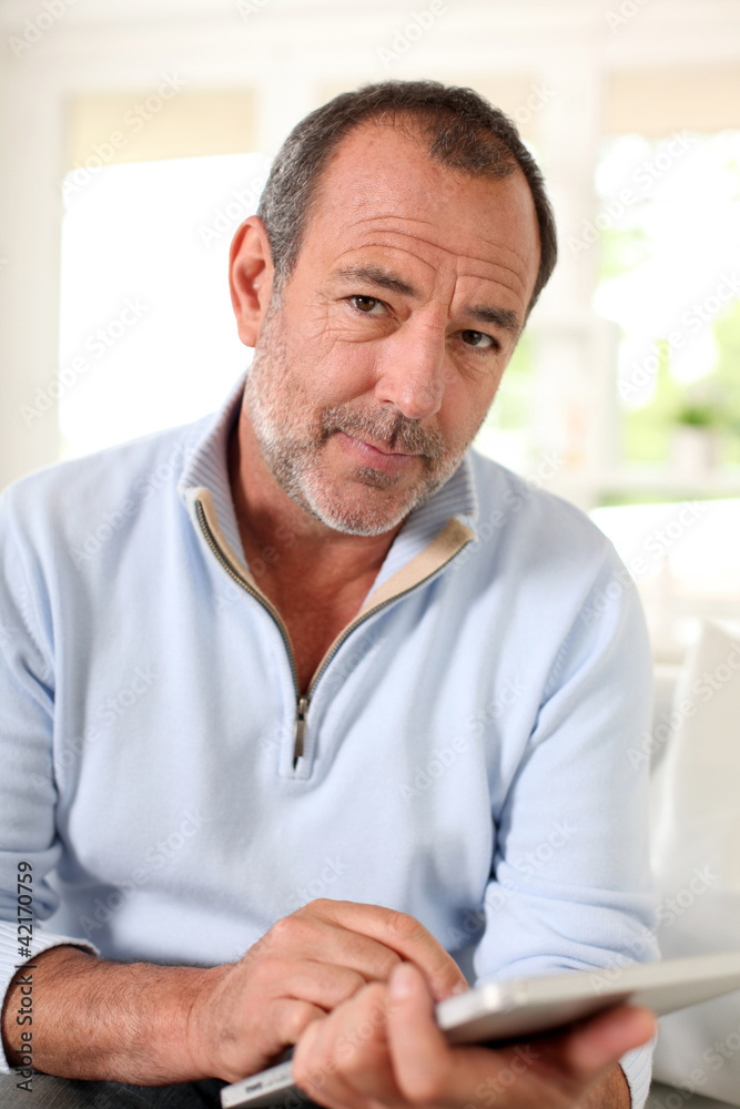 Senior man at home using electronic tablet