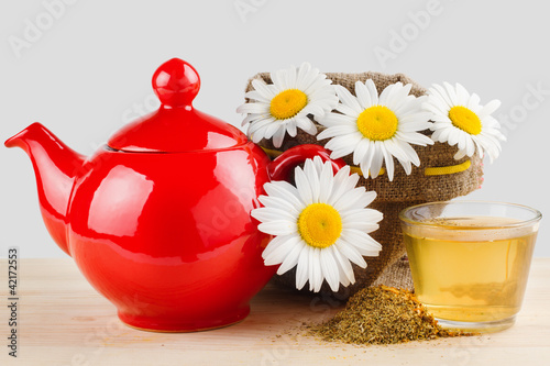 healthy chamomile tea, red teapot and sack with daisies