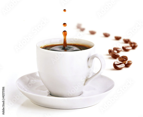A cup of coffee with a splash of drops and coffee beans.