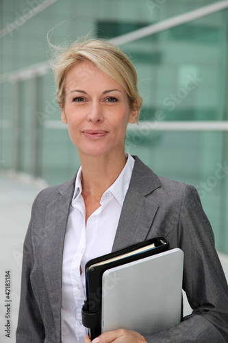 Mature businesswoman standing in front of modern building photo