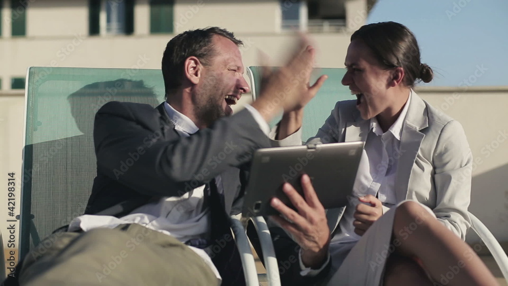 Successful business couple with tablet computer lying on sunbeds