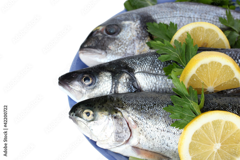 Fresh fishes with lemon and parsley on plate isolated on white Fresh fishes with lemon and parsley on plate isolated on white