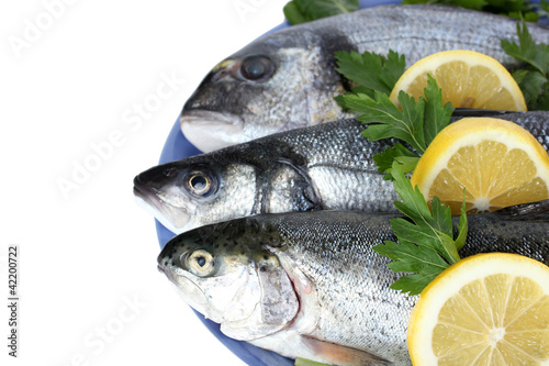 Fresh fishes with lemon and parsley on plate isolated on white