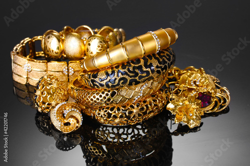 Beautiful golden bracelets, rings and jewelry on grey background