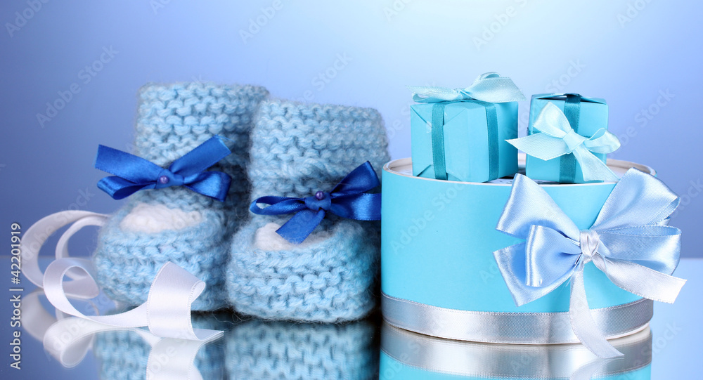 beautiful gifts and baby's bootees on blue background beautiful gifts and baby's bootees on blue background