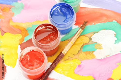 Jars with colorful gouache on a bright picture close-up