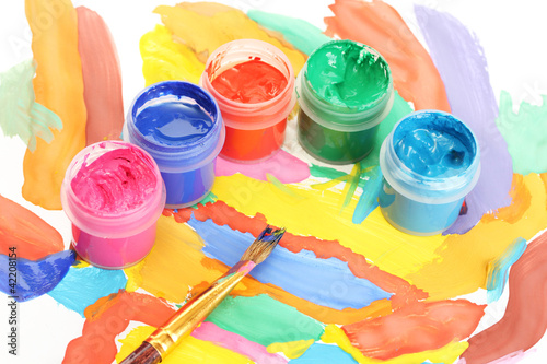 Jars with colorful gouache on a bright picture close-up