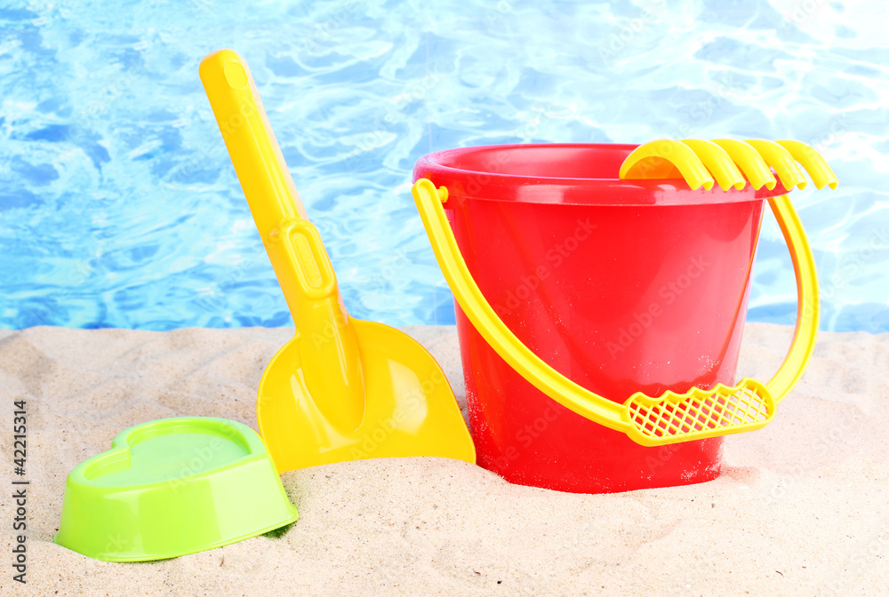 Children's beach toys on sand on water background Children's beach toys on sand on water background