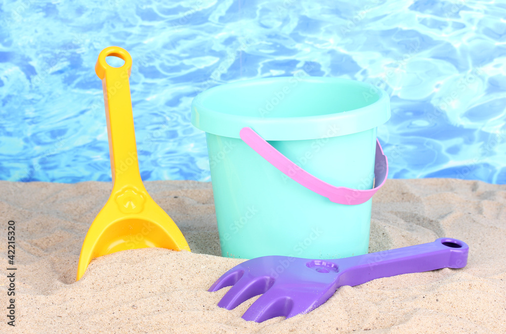 Children's beach toys on sand on water background Children's beach toys on sand on water background