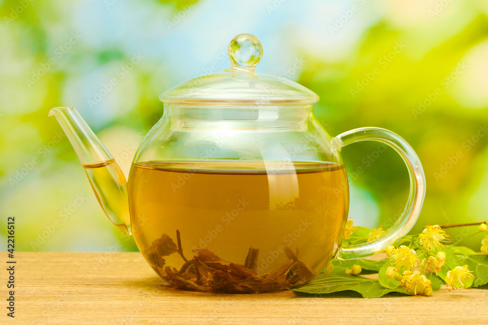 linden tea in teapot and flowers on wooden table in garden. linden tea in teapot and flowers on wooden table in garden.