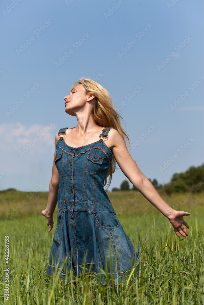 Obraz premium The happy young woman in the field of green ears