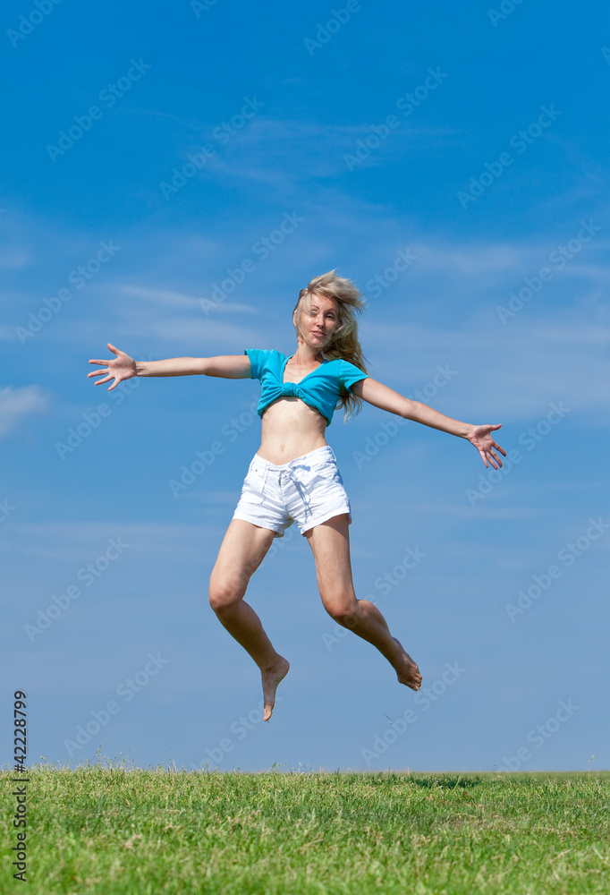 The happy young woman jumps in the field The happy young woman jumps in the field