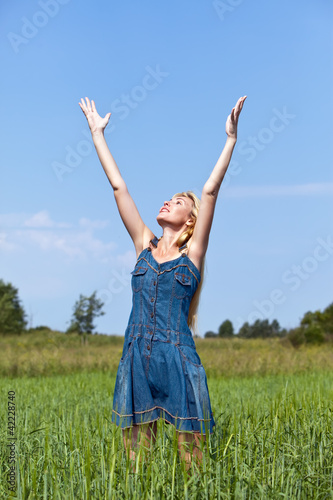 The happy young woman in the field of green ears