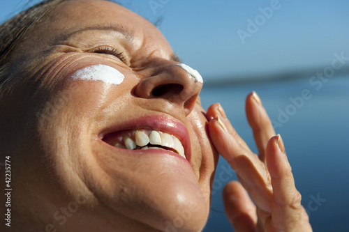 Happy woman sun protection on face
