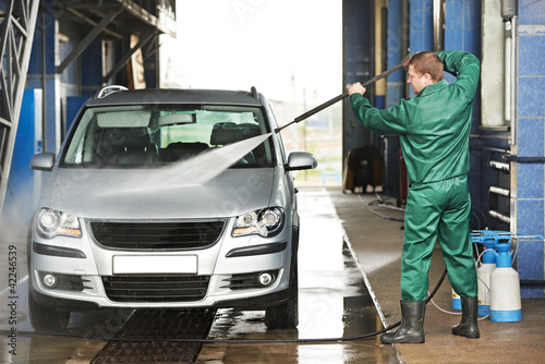 worker cleaning car with pressured water