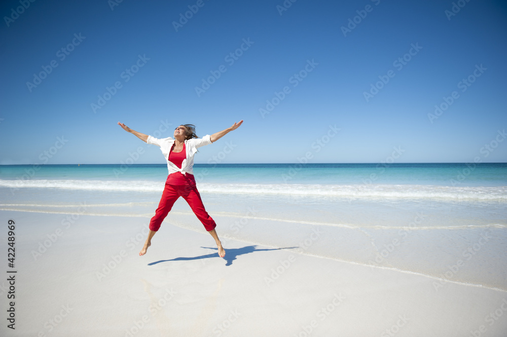 Joyful mature woman jumping tropical beach Joyful mature woman jumping tropical beach