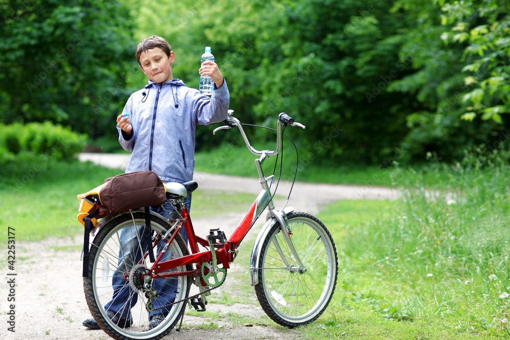 Young boy with bicycle with clear water relaxing outdoors
