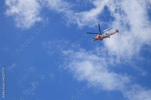 Helicopter rescue in flight against blue sky background.