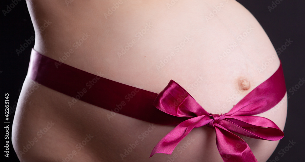 Pregnancy. Abdomen. Red Ribbon. Black background Pregnancy. Abdomen. Red Ribbon. Black background