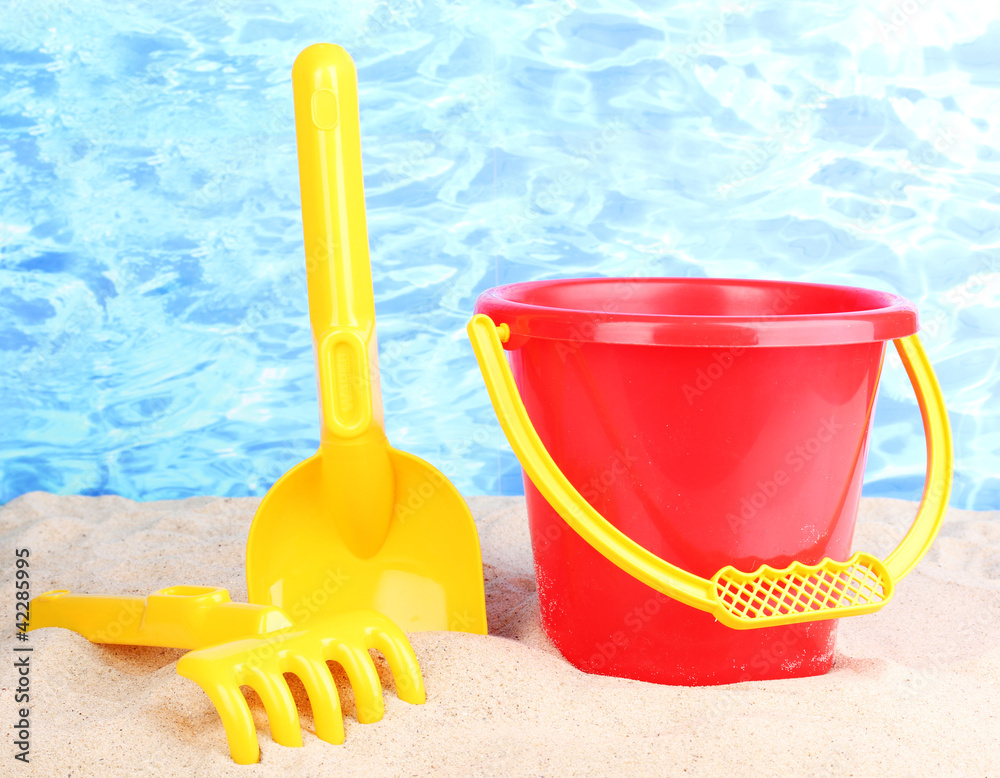 Children's beach toys on sand on water background Children's beach toys on sand on water background