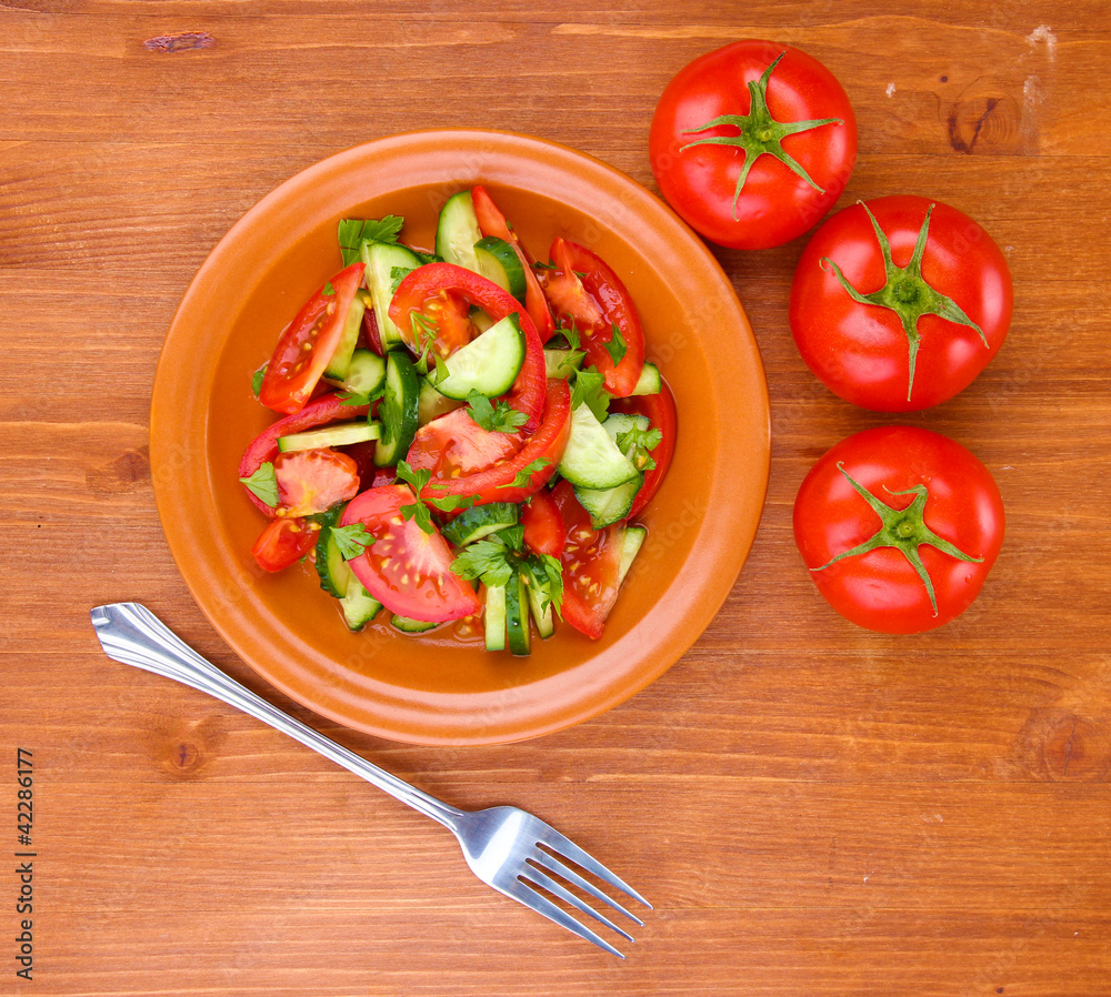 Fresh salad with tomatoes and cucumbers on wooden background Fresh salad with tomatoes and cucumbers on wooden background