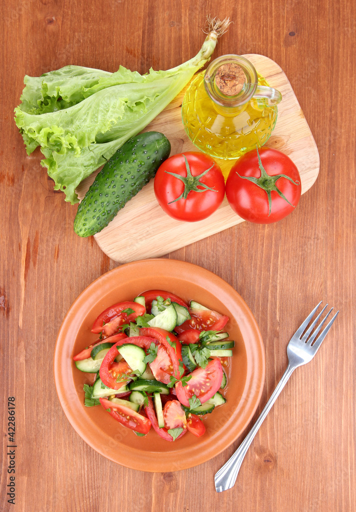 Fresh salad with tomatoes and cucumbers on wooden background Fresh salad with tomatoes and cucumbers on wooden background