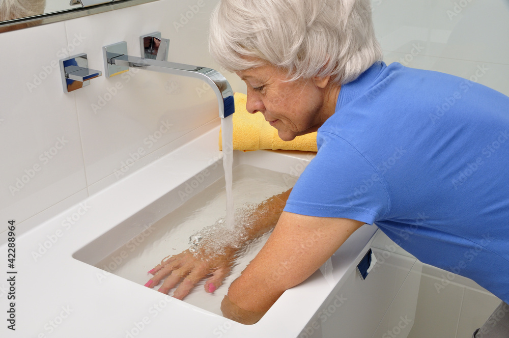 Fototapeta premium Seniorin macht Wechselbäder im Waschbecken