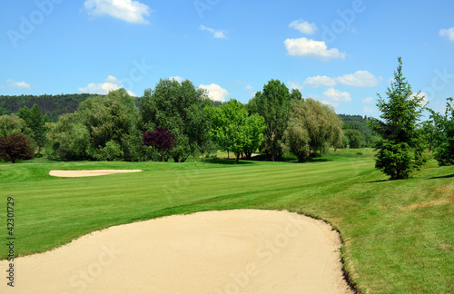 Golf course, green grass, large sand pit, trees