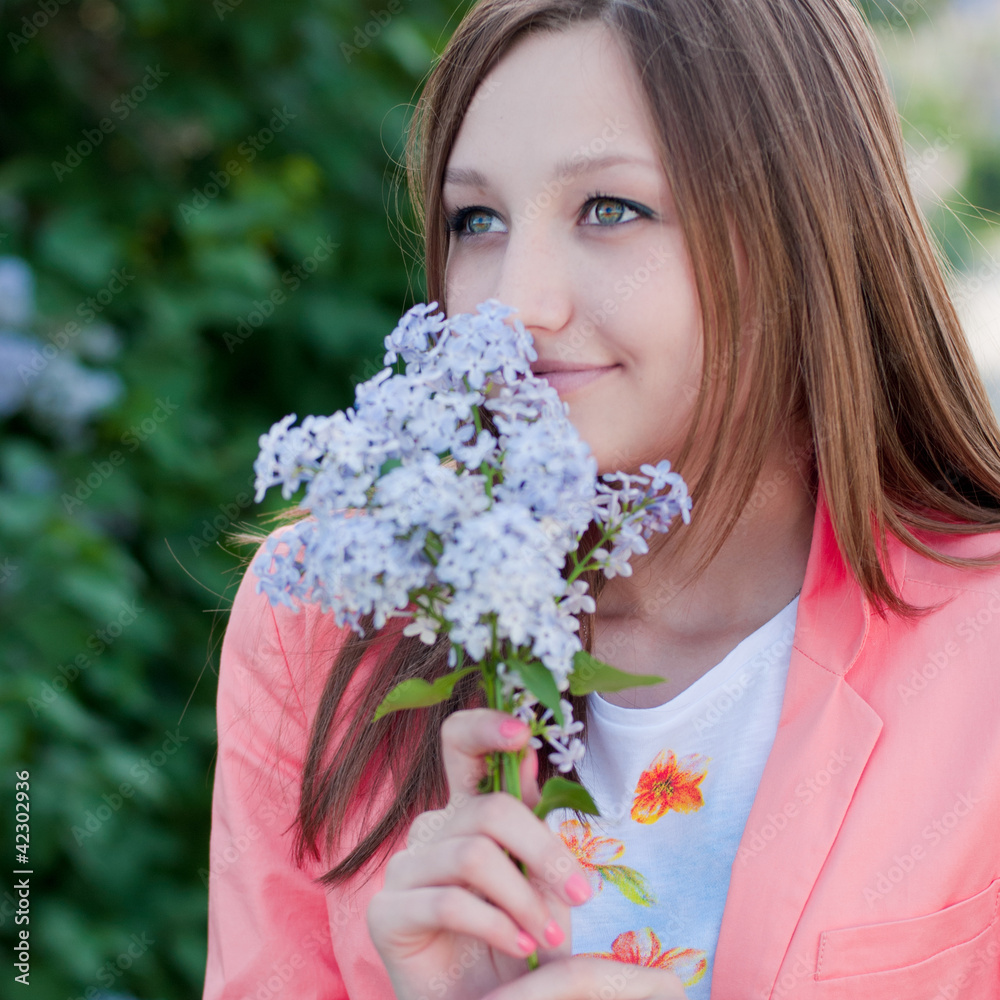 Fototapeta premium Young pretty girl smelling lilac flower