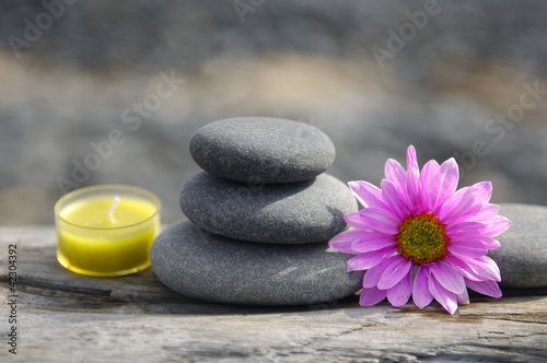 candle with stacked stone with Gerbera Daisy flower