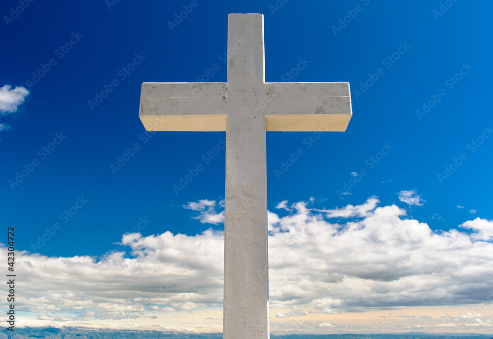 White cross against blue sky and fluffy clouds White cross against blue sky and fluffy clouds