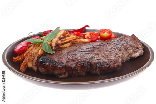 beef steak on dark plate with red hot chili pepper