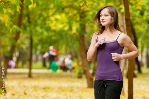 Fototapeta Naklejka Na Ścianę i Meble -  A young girl running in autumn park