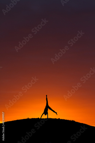 silhouette o kid doing a cartwheel in sunset