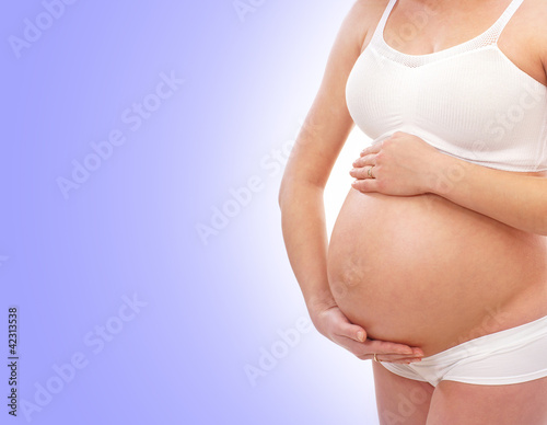 Belly of a young pregnant woman on a blue background