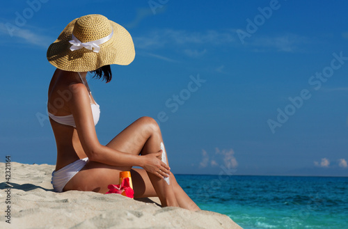 Slim woman applying sunscreen