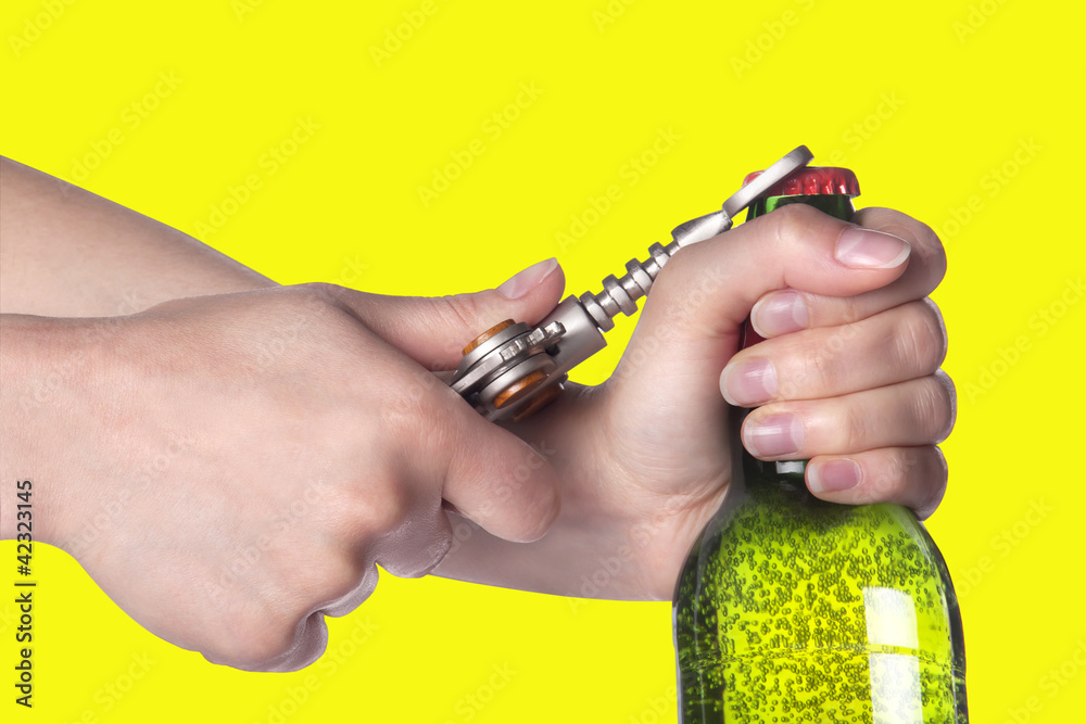 Fototapeta premium hand opening beer bottle with metal opener