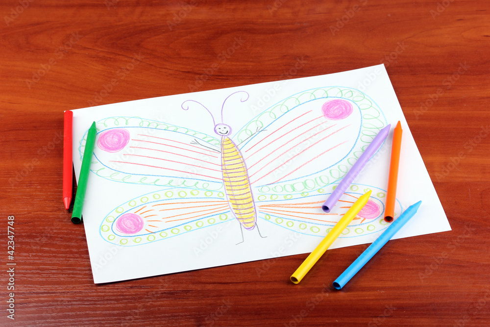 Children's drawing of butterfly and pencils on wooden Children's drawing of butterfly and pencils on wooden