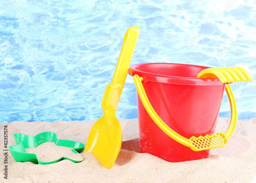 Children's beach toys on sand on water background Children's beach toys on sand on water background