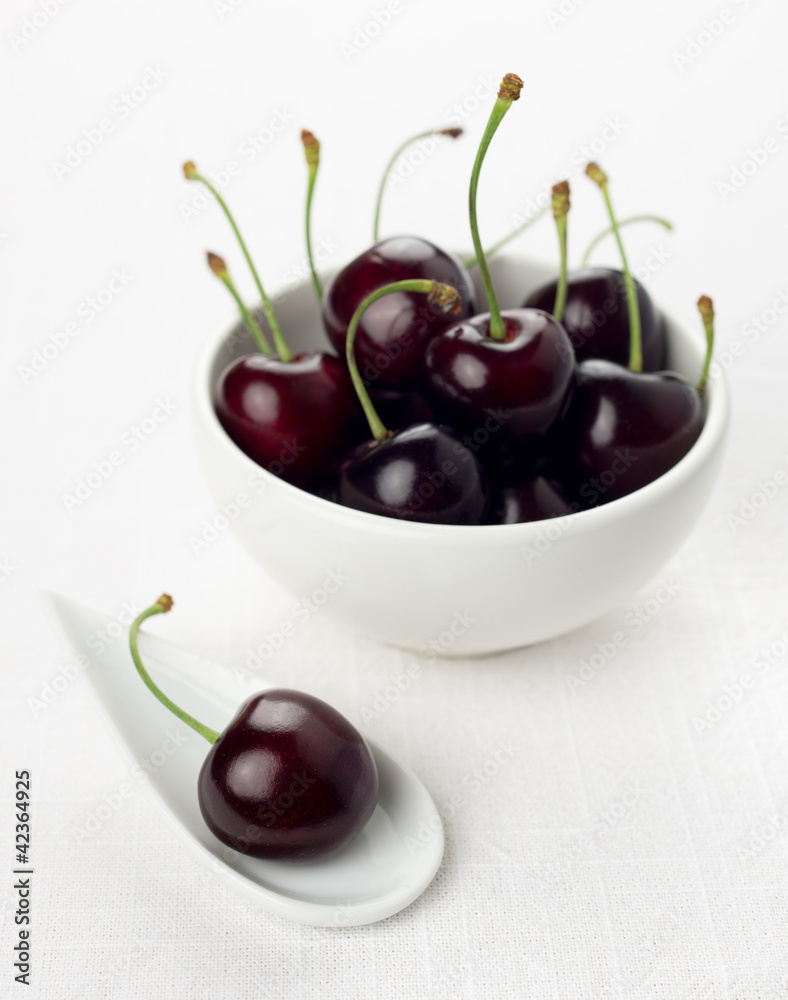 Cherry on white china spoon, cherries group in a white bowl Cherry on white china spoon, cherries group in a white bowl