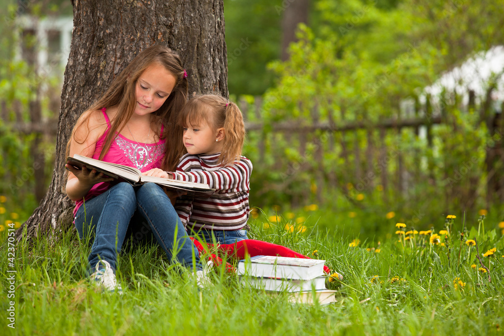 Children reading the book in summer park Children reading the book in summer park