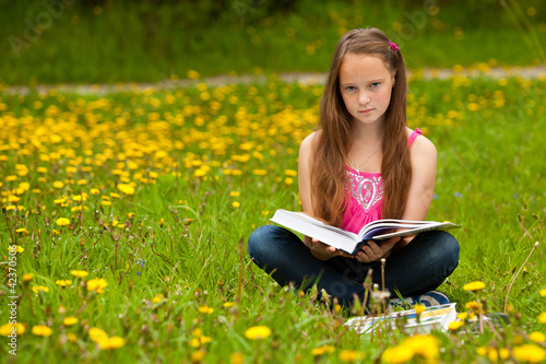 A girl 11 years old reads a book in the meadow © De Visu